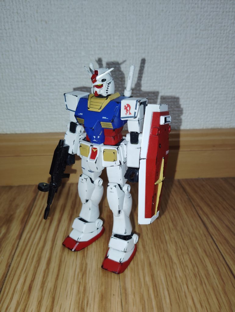 　正面素立ちです。　使用したキットは、ガンダムとザクがセットになった「ガンプラスターターセット」なるキットのガンダム（ようするに旧HGUC ガンダムのカラーバリエーション）です。　４年ほど前に５０投稿目記念作品としてガンスタに投稿した「辞令。第04MS小隊を、オデッサ基地防衛に派遣する」に登場する、ジョン・ブラック曹長のザクの相方（？）を、今回の投稿に向けて製作しました。　基本塗装は、ツヤ消し白とインディブルー、赤とクリームイエローです。　ガンダムの特徴のひとつでもあるツインアイは、下地を銀色で塗装したうえからクリアーイエローを塗って再現しました。　マーキングを施したあと、ツインアイや額のメインカメラなどをマスキングテープで保護してから、ツヤ消しトップコートを吹いてあります。　スミ入れは、いつも通りシャープペンです。　仕上げに黒鉄色で全身にウェザリングを施しました。