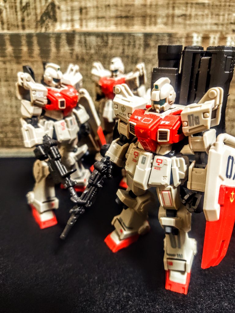 3つもいると、1つは素のスタイル。もう1つは拡張、最後はとりま付けたくると、まぁこうなるわけですよ。それで言うと今回は2つめの機体にコンテナやパラシュートをつけたかったんですよね。なかなかうまくモノが見つからず、3つめに武器を背負わせて終わってしまったと。陸戦型で背負ったコンテナが大きすぎたので（笑）、何か違うもの、と思って飾られて忘れられてしまったわけ。けれど3機もいると嬉しくなります。(実際にはもっとあるんですが)所謂1/144スケールと違って、ちょっとだけ小さいんですよね。なので集めやすくて、買ってしまって、その時武器を揃えたくてもれなく陸戦型ガンダムも1個追加されます。(マシンガン欲しくて)