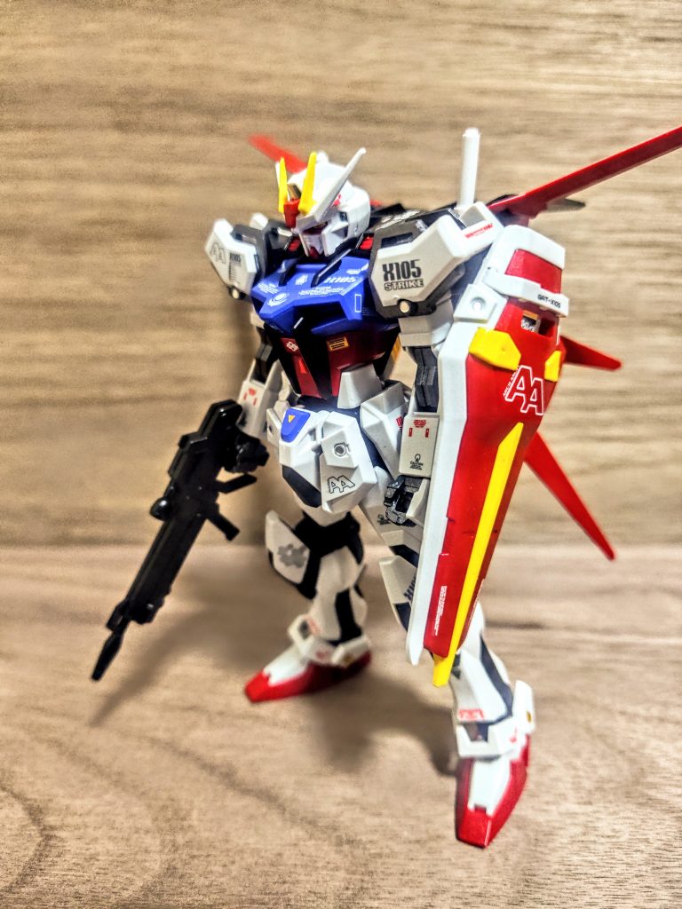 というのをほとんどのパーツを外して、持ち手棒でつまんでから塗りまくったのが上のノーマルカラー版ストライクです（笑）。ただ、こちらは通常のエントリーグレードから作ったので、オリジナルカラー版に付けた胸の先端のデザインチップがありません。そこだけ色が合わなくなる気がして（泣）。これはひとえに、「サーフェイサーを塗らないから（笑）」いけませんねぇ、これは来年の年末までには絶対にやらなくちゃいけない事ですね。来年の目標はサーフェイサーとエアブラシ投入、これにしましょ。思えば私のようなかけだしヒヨッコは缶スプレーなので。と言ってもこれも工夫次第で、先に塗っておいたデザインチップを胸パーツに貼って、その後もう一度胸パーツごと塗装したら行けそうな気もします。ようは手抜きです、ごめんなさい。