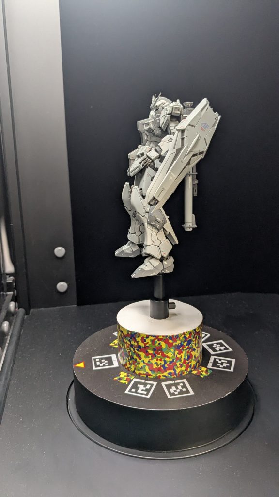 そしてポージング全てしてもらい笑、スキャナーに設置です！RGνの股関節は可動部がある為、お尻側のパーツに3mm軸穴を空けておきましたが、大した問題では無いものの、リグ入れに影響してしまいました。また、ビームライフルはオリジナルCGモデルが勝手に表示されるとの事で、外しました。ロングレンジフィンファンネルは付けたまま行けるか？と思いましたが、スタッフさんによるとおそらく先の方が切れてカッコ悪くなりそう…との事で外す事に。バックパックのバズーカはそのままにしました。しかしこれもリグ入れの際に、少々面倒な事に…。