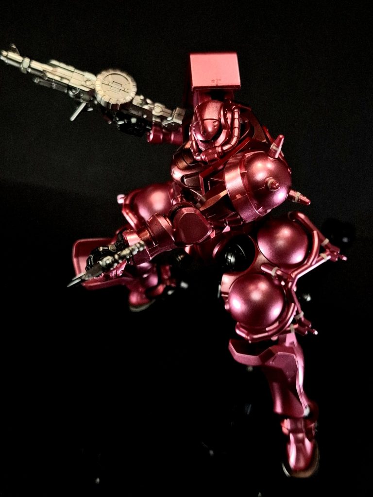 ザク・マシンガン編集ザクが使用するMS用マシンガンの総称[53][注 12]。通称はザク・マシンガン[54]であるが、ライフルと表記した資料も見られる[注 14]。接近戦用の装備とも称され、単発と連射の切り替えが可能[55]。弾薬は主に薬室上部の円盤型弾倉（パンマガジン。ただし、設定上の呼称は「ドラムマガジン」）から供給される[56][注 15]。状況に応じて破壊力を重視した榴弾や徹甲榴弾を使用する[57]。『ポケットの中の戦争 フィルムブック 2巻』によると[53]、当初は従来式の大砲に発射スイッチを仕掛けた単純な物を想定していたが、重量や反動での損傷、宇宙空間での姿勢制御など多数の問題点から方針を変更。続いて1G下で400-500m/秒程度で曲射弾道の射撃を行うことを目指したが、MSが戦艦に肉薄できると判明したことで初速への要求値が100m/秒に引き下げられる。さらに断続的な射撃より連射が有効と判断され、低反動低初速で榴弾を連射するというコンセプトで開発が進行した。作動機構はガス圧式や反動利用式などが挙がっていたが、最終的に電気作動式が採用されている。