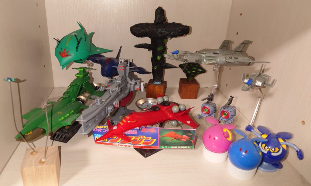 『製作へのこだわり』 大前提として最初のタイトルであげたように「かっこいいMSを作りたい」があります ならば「かっこいい」とは何か?以下の三点が私の考えるかっこ良さの構成要件です ①実存性を高める ガンプラは子供に買わせたい為に原色を多様したものですが、年を経るにつれて物足りなくなりました 皆様も同じと思いますが、「現実に存在する姿を見たい」と思った時、オリジナルカラーはあまりにも派手… 実在の兵器や建設機械を見れば地味な色で無骨な存在です まず出来るのは単純なカラーの変更です ②ミリタリー属性を強める 参考になるのは実際の兵器と歴史です 具体的には第一次世界大戦から現代のウクライナ戦争(未だ終わりを見ない戦争に安直に呼ぶべきではないかもしれませんが)に至るまでの兵器と戦い方の変遷です 戦争は時代・地域・状況により千差万別 どれ一つ同じものがありません ただ、そこに生きる人々は誰しも「故郷を守って再び帰りたい」という切なる思いがあります そう考えた時、兵器はその土地の色・気候に合わせた色に変えられます 鉄の黒からグレーやジャングル迷彩、砂漠迷彩、冬季迷彩などなど…私もそれを意図して色を決めています ③ポージングへのこだわり 撮影やポージングが上手い人は世間に沢山いらっしゃるので、私ごときが言うのは烏滸がましいですが、参考にしている言葉があります 文化勲章を授与された彫刻家・中村晋也(なかむら しんや)先生の言葉です 「私はその人物がもっとも輝いていた瞬間を切り取って表現したい」 意訳ですが、これは先生と対面して直に伺った言葉です 先生は日展での作品発表の他、日本各地で歴史上の人物の銅像製作にもあたられています 鹿児島市の大久保利通卿立像やJR伊集院駅前の島津義弘公騎馬銅像、熊本県菊池市の菊池武光公騎馬銅像、宮城県の片倉景綱公坐像など…興味を持たれた方は調べてみて下さい MSが最高に輝いた瞬間を考えると、やはり戦闘の一瞬を切り取った状況でしょう 故に私はMSのモノアイやツインアイ越しの視線と銃口・砲口は一致させます 敵を倒そうとする者が、相手から視線をそらすことは死を意味します そこさえ抑えれば、あとは劇中の名シーンを真似ていけばいいと思います