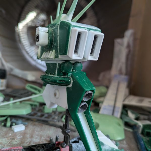 なんとか上半身は、完成できました。バックパックを上にずらした時、異常に腰が上がっていたのでよく見てみたら、元のデザインとキットの造形違いに気づき、首の後ろを4ミリ程下げる工作をしました。背面がかなり自然に見えるようになったと思います。腕は、上腕にロール軸を追加し、ケーブルっぽい部分をカットして、別パーツを付ける予定です。コードかスプリングかは検討中。肘は元のデザイン上、関節がないことに驚きました。検討した結果、キットのままです。手の爪は、100円ショップで3ミリのビーズを見つけたので、これでボールジョイント接続にしました。受けはセリアのプラ板が予想以上に柔らかいことを利用し、基部に3ミリの穴を空けて取り付けたところ、いい具合に渋みのある関節になりました。頭部のパイプは、100円ショップの手芸コーナーで見つけた、ヤーンという飾り紐で太さが2ミリと丁度良かったため、採用しました。肩は可動を諦め、3ミリ棒での接続にしてあります。腰回りは、胴体を幅詰めした分、調整が必要なのと、可動が必須なので後回しにして、これから脚部の改造を始めます。REのアレンジは参考にできないので、試行錯誤になりますが、元のデザインと可動をどうするか、これから検討します。正月明けには、塗装待ちくらいにまでは完成させたいと思いますので、温かく見守って下さい。それでは皆様良いお年を。（3枚目）