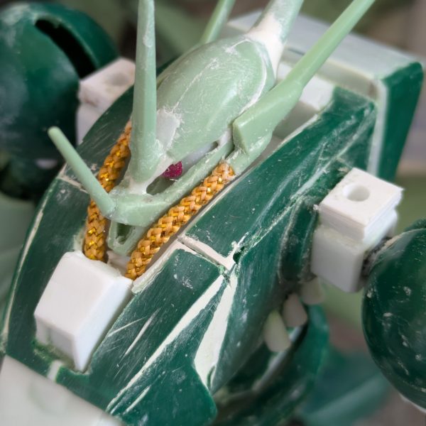 なんとか上半身は、完成できました。バックパックを上にずらした時、異常に腰が上がっていたのでよく見てみたら、元のデザインとキットの造形違いに気づき、首の後ろを4ミリ程下げる工作をしました。背面がかなり自然に見えるようになったと思います。腕は、上腕にロール軸を追加し、ケーブルっぽい部分をカットして、別パーツを付ける予定です。コードかスプリングかは検討中。肘は元のデザイン上、関節がないことに驚きました。検討した結果、キットのままです。手の爪は、100円ショップで3ミリのビーズを見つけたので、これでボールジョイント接続にしました。受けはセリアのプラ板が予想以上に柔らかいことを利用し、基部に3ミリの穴を空けて取り付けたところ、いい具合に渋みのある関節になりました。頭部のパイプは、100円ショップの手芸コーナーで見つけた、ヤーンという飾り紐で太さが2ミリと丁度良かったため、採用しました。肩は可動を諦め、3ミリ棒での接続にしてあります。腰回りは、胴体を幅詰めした分、調整が必要なのと、可動が必須なので後回しにして、これから脚部の改造を始めます。REのアレンジは参考にできないので、試行錯誤になりますが、元のデザインと可動をどうするか、これから検討します。正月明けには、塗装待ちくらいにまでは完成させたいと思いますので、温かく見守って下さい。それでは皆様良いお年を。（6枚目）