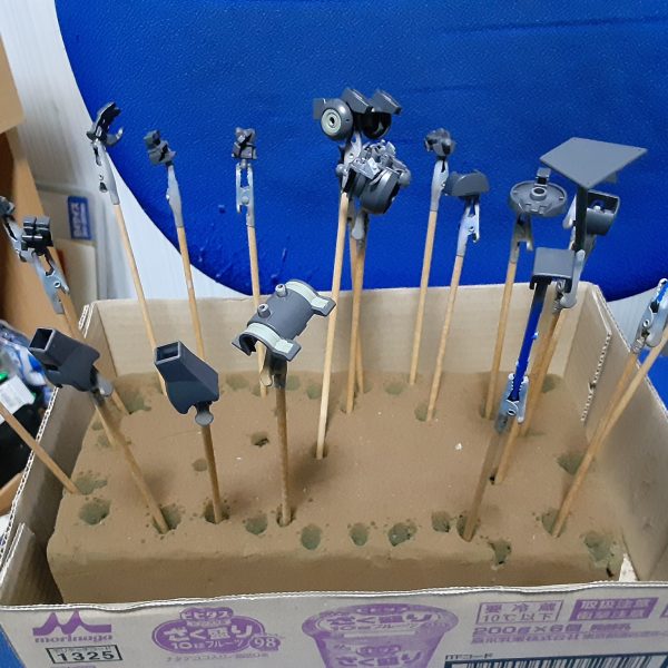 雨だったり暑すぎたり農家の仕事があったりと、色々理由を付けて塗装作業から逃げていたデミギャリソン。久しぶりに引っ張り出して、脛やバックパックを塗装。&nbsp;写真中央に写っているのは左がバックパック、右が腹部下段のパーツ。黒い部分を塗った後、マスキングを剥がして先に塗った薄いグレーの部分を見えるようにしたのがこの状態。設定画ではバックパック全体が同じ色ですが、何色かで塗り分けるとフレームが露出していたり、違う素材が使われているように見える・・・はず！&nbsp;薄いグレーはRLM02グレー、黒はジークアクス用のダークグレー。写真だと何故か青みがかって見えますが、このダークグレーは実際には茶系のグレーです。（2枚目）