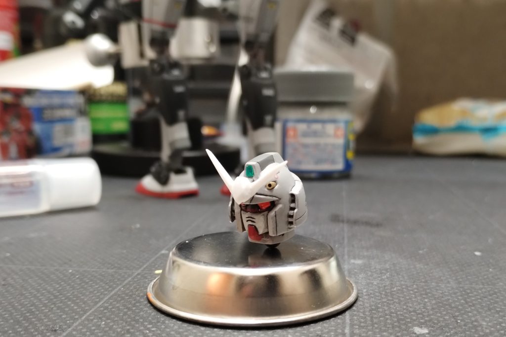 プラ板でV字アンテナを作り、メインカメラにはクリアグリーンのUVレジン。目にはクリアピンクのパーツ、頭部バルカンには真鍮パイプを使っています。