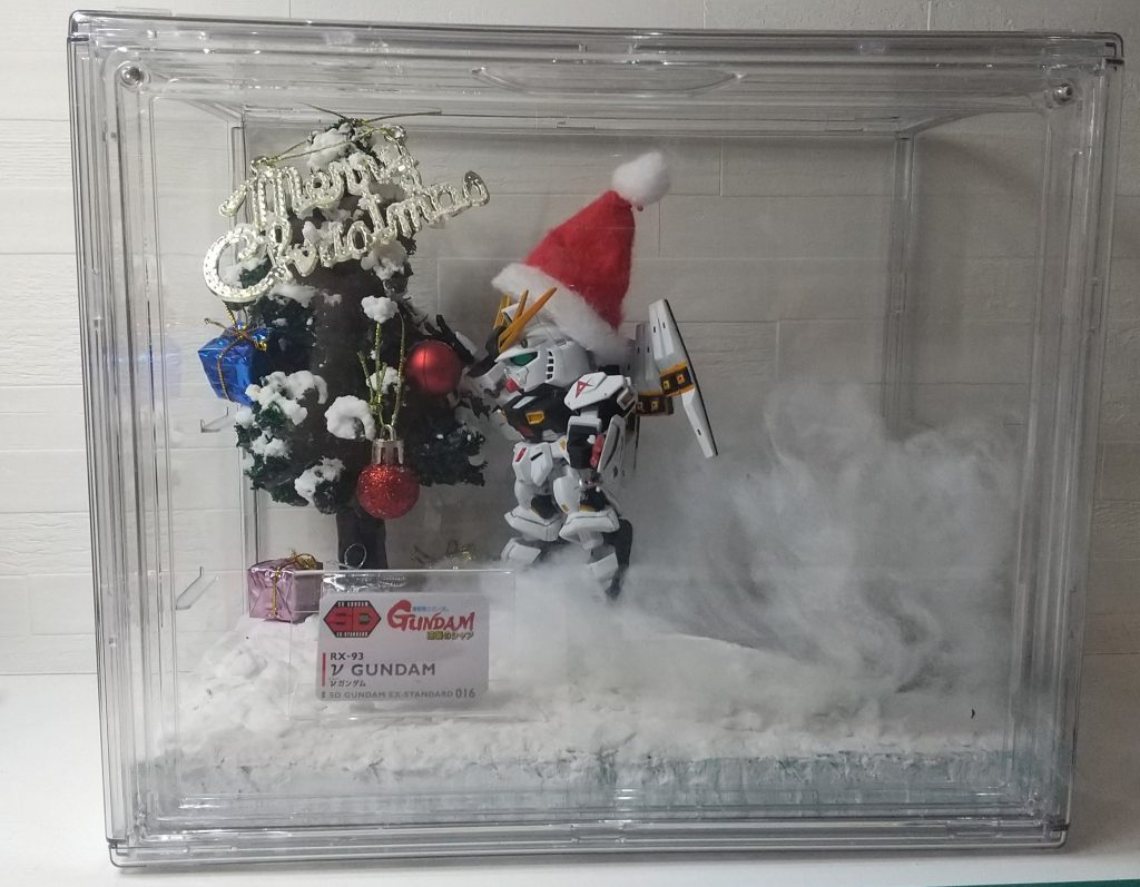 ジオラマはAmazonで買ったディスプレイケース1600円ぐらいのやつの中に作りました。クリスマスツリーは、割り箸に針金を枝のように巻き、紙粘土を貼って100均のアクリルガッシュで木を塗装。ダイソーのグリーンモスという謎の草を細かく切って木工用ボンドで混ぜて貼っていく。土台はセリアのポリエチレンボードに紙粘土、その上から重曹と木工用ボンドを混ぜたものを乗せていく。ツリーにも重曹の雪を枝の先端に置いていく。飛んで雪けむりが上がる演出の為、地面を土にした部分がうっすら見えている。土の部分はボンドの上にコーヒー豆をパラパラ撒いて、その上からアクリルガッシュで塗って土っぽくして、綿をふわ～っとおいてあるだけ。ダイソーで買ったオーナメントを飾り、サザビーのコクピット風に持たせてみたりｗ左下が寂しかったので、ガンプラの箱の逆襲のシャアとか型番の部分をダイソーのL型カードスタンドに入れて飾ってた。