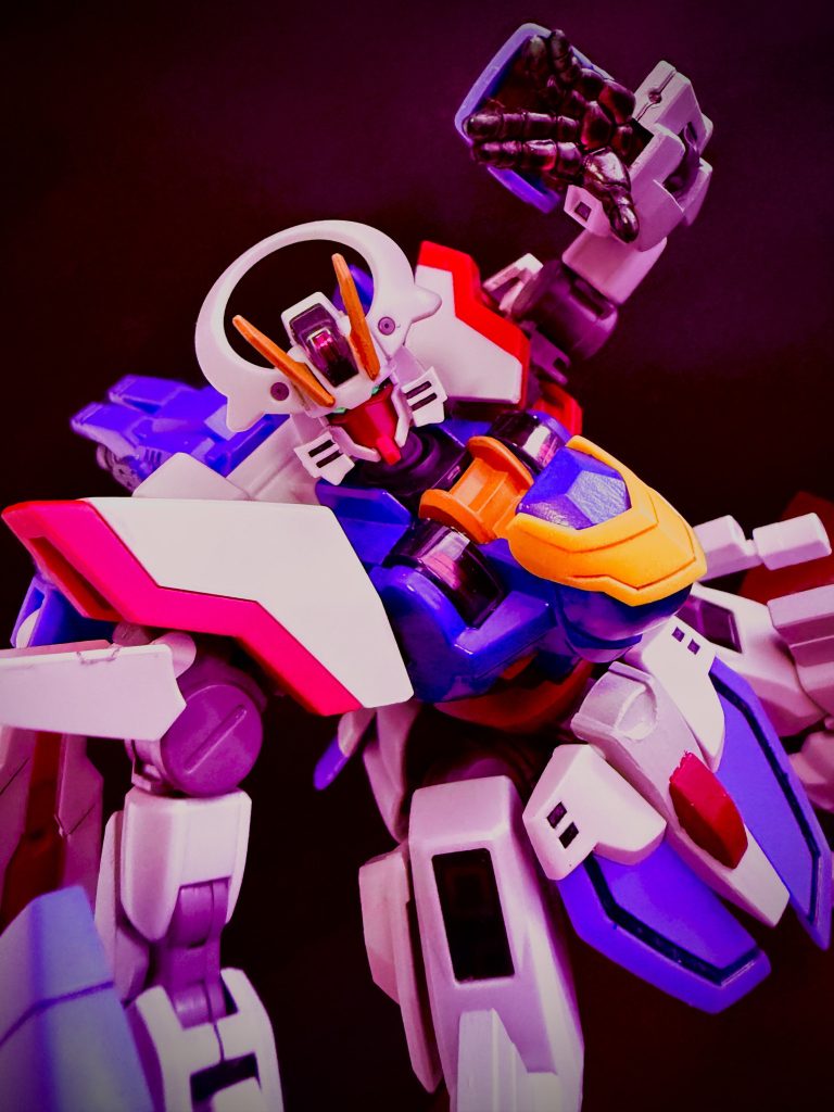 「気ぃ炮ッ暗黒通ッ！！！」　土門の放った拳は、ガバリと指をひらくと、リーダー機のディランザの頭部をモヒカン状の派手な頭飾りもろとも握り潰す。紫色の禍々しい光を宿す指は、ミシミシと不気味な音を立てながらディランザの頭部装甲をひしゃげさせ、メリメリとその指を埋没させていく。「ウォォォッ！」　コクピットの中で土門が吠える。ディランザの頭部を握り潰している腕が、指が焼ける様に痛い。しかし、負の感情に支配された土門は、それでもディランザの頭部を握った手を緩めない。どんどんと握り締めていくうち、いつしかコクピットの中には、土門の声とは別に、リーダーの声が混ざってくる。リーダーの悲鳴だ。彼の乗るディランザは当然のことながら通常のMSだ。機体のダメージがパイロットに伝わる事はない。彼の悲鳴は純粋な恐怖から来るものなのだ。そんな自身の雄叫びと、リーダーの悲鳴が混じり合うコクピットの中で、土門は渾身の力でもって、自らの拳を閉じた。　…決闘は終わった。　1対15という圧倒的とも言える戦力差を覆した土門だったが、誰も彼に賛辞を贈るものはいなかった。…克州土門の初めての決闘は、謳われざる勝利を手にしたのだった。　…そんな土門の勝利を、静かに見守る者がいた。学園の時計塔。その屋根、尖塔の先に男が立っているのだ。長い白髪の総髪をキリリと後ろで束ね、薄紫色の胴着に身を包んだ男だ。ヒゲをたくわえ、鋭い眼光の中に慈愛の光を湛えた男は、誰に言うまでもなく一人静かに言う。「フフフ…。腕を上げた様だな、土門。…だが、あの程度の相手に苦戦している様ではな」　と、言葉の割に何処か満足そうに小さく笑みを浮かべると、キリリと中を見据え、「…良し、次はワシが自ら相手をしてやろう」　そう言った瞬間、尖塔の先にその男の姿は無く、まるで初めから誰もいなかったかの様に、風だけが吹いていた。