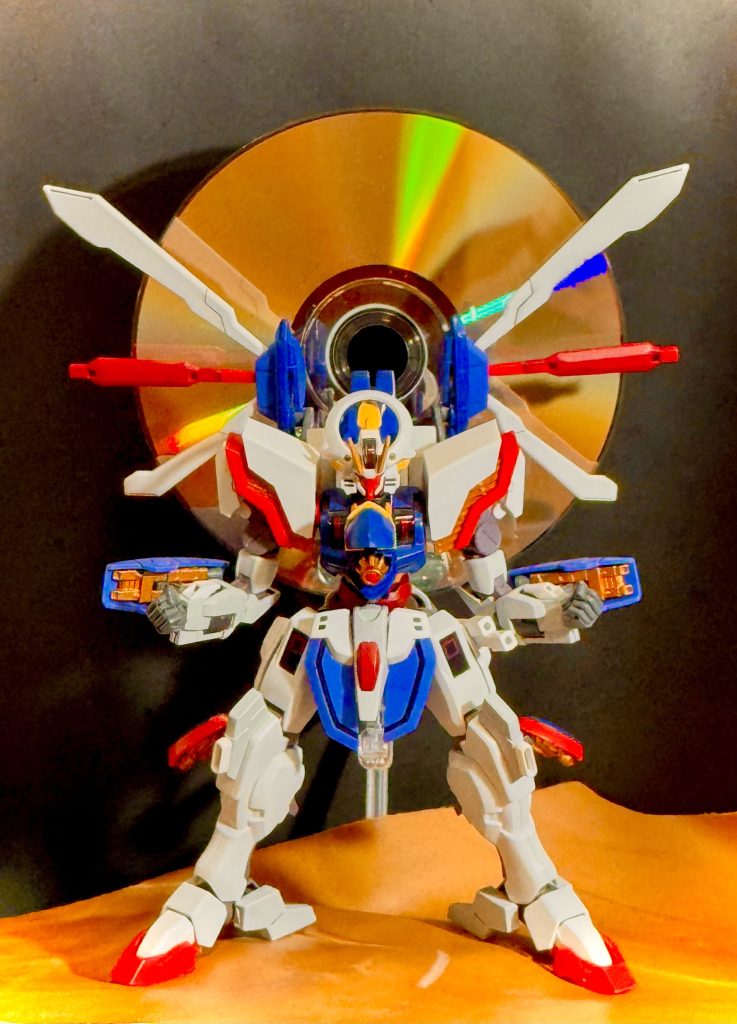 「いくぞッ！東方無敗ッ！！」　土門が吠える！それに呼応するようにシャイニングガンダムも機体各部を展開させ、スーパーモードとなっていく。同時にシェルユニットの輝きが増していく。土門が込める気合いは、それ自体がエネルギーとなり、シャイニングガンダムの機体を通して噴出され、周りの岩塊を宙に浮かび上がらせる。「オォォッ！」「来いっ！土門！…今こそ決着の時ぞっ！」　土門の雄叫びに、東方無敗の叫びが重なる。向かい合う二機、シャイニングガンダムとマスターガンダムは、それぞれの機体から凄まじいまでのエネルギーを噴出させている。そのエネルギーは、二機を中心に混ざり合い巨大な竜巻となって拡がっていく。　凄まじい光、エネルギーの奔流の中、二機のガンダムにある異変が起きる。シェルユニットの光が黄金色の輝きをもってきたのだ。その輝きはシェルユニットの中だけではとどまらず、その眩い黄金色の光は、機体の表面、装甲、関節部までもが輝いていく。「おお！ついに、ついに到達したのだな！明鏡止水の心境に！」　黄金色の光を全身に纏うシャイニングガンダムを前に、東方無敗はこれから始まるのが殺し合いだという事も忘れ感嘆する。「良いぞ！土門！…見つけたのだな。お前自身の黄金のひとしずくを！」　…ワシは良い弟子を得た。東方無敗は師としての喜びをのせ叫ぶ。向かいに立つシャイニングガンダム同様、黄金色に染まった両の拳を突き出し叫ぶ。「ゆくぞぉ！土門っ！流派ぁ！東方無敗が最終奥義ぃっ！！」「応ッ！」　同じ様に両の拳を前に突き出した土門も吠える！…それは、流派東方無敗の最終奥義の構え。　…二人の声が重なる。「「石破ッ！」」「「天ッ驚拳ッ！！」」　…土門が吠える。東方無敗が吠える。二人の咆哮は大地を揺るがし、空気を揺るがす。ぶつかり合う光と光。二機のガンダムが放った石破天驚拳は、向かい合う二機の中心でぶつかると、暴力的な渦を発生させる。縦に横に拡がり回転する巨大な渦は、大地を、木々を、空気さえ巻き込んで土門を、東方無敗をその光の中に飲み込んでいく。「うぉぉッ！…か、身体がバラバラになりそうだ。…こ、これが師匠の本当の力なのか」　技と技、エネルギーとエネルギー、気と気のぶつかり合い。その凄まじいエネルギーの奔流に、土門の身体は早くも悲鳴をあげ始めていた。拳を通し放つ気のエネルギーは、仮に生身で放ったとしても並のMSなら破壊出来る程の威力を持つ。…流派東方無敗の奥義たる所以だ。その奥義を土門は今、真正面から受けている。…しかし、それは東方無敗も同じであり、もはや、我慢比べの様になっている。互いに渾身の力を込めた気を放ち、強大なエネルギーの塊となった暴力そのものといえる光を全身にくらい続ける二人。　その命を賭けた我慢比べもいよいよ終焉の時が訪れる。限界の来た土門の身体が揺らぎ始めたのだ。…意識を失いかけた土門が片膝をついてしまう。「…何をしている！土門！自ら膝をつくなど勝負を棄てる者のすることぞ！！」　東方無敗が吠える！「立て！土門っ！そんなことでは悪党のワシ一人斃すことなぞ出来んぞ！…このバカ弟子めがっ！立て、…立ってみせいっ！！」　東方無敗もまた、限界なのだ。ギリギリの身体を軋ませ東方無敗は、気を放つ。放たれた気は渦巻く光の玉となり、膝をついたシャイニングガンダムの、土門の腹を打ちつけると、土門を無理やり立たせる。「うぐわぁッ！」　その一撃が気付となった土門は、両の目を開き気合を入れ直すと、眼前のマスターガンダムを、東方無敗を見据え、再び自らが打ち出している光の奔流に力を込める。「そうだ！東方無敗ッ！俺は、…俺はアンタを超える！超えてみせるッ！」　叫ぶ。土門から溢れる光が、シャイニングガンダムから放たれる光が、黄金色の光が、一層の輝きを、強さを増し、二機のガンダムを包み込む。「ウォォォッ！ばぁくねつッ！！石ッ破ッ！天ッ驚ォォッ！シャァァイニングゥッ！フィンガァァァァッーー！！！！」　圧倒的な光。石破天驚拳に上乗せされたシャイニングフィンガーのパワーが、エネルギーが巨大な手となり、マスターガンダムを、東方無敗の身体をガッシリと掴む。「うおあぁぁぁっ！！」　東方無敗が吠える。この瞬間、土門は自身の最高の奥義を会得したのだ。　…完全に自分の力を凌駕した光に身を包まれながら、東方無敗は思い返す。…修行に明け暮れた若き日を。…土門を弟子として共に過ごした日々を。…目を瞑り思い返す。ワシは、良い弟子をもったと…。光に包まれた東方無敗は、目をカッと見開き拳を掲げると、静かに、そして力強く言う。その拳にはハートの紋を背に立つ王の姿が浮かび上がっている。「…良し。今こそ、お前は本物のキングオブハート」　土門は見た。自らの放った光の奔流の中にマスターガンダムの姿がきえていくのを。土門は聞いた。光の中に消える東方無敗が、穏やかな笑みを浮かべ、話すのを。「……ッ！」　師の想い。師から託されたものに気付く土門。師匠ッ！…しかし、時はすでに遅く、土門の放った技は完全に決まっているのだ。「うわぁぁぁッ！…シャァァイニングッ！…エェーンドォォッ！！」　…コクピットの中で、土門は叫ぶ。涙でもう何も見えない土門は、ただただ、叫び、涙し、自分の手を握り締めることしかできなかった…。