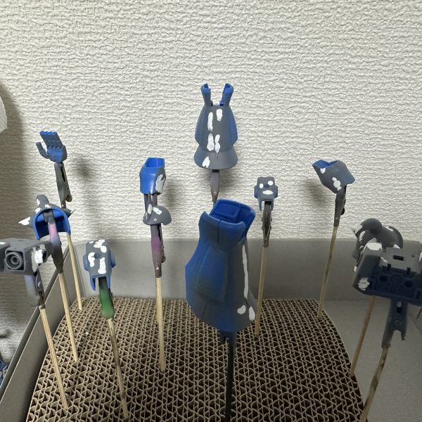 HGグフをキャンディ塗装で製作中。現在はパーツの乾燥待ちです。 合わせ目を消すために太ももと腕関節のあとハメ加工を施し、合わせ目消し→捨てサフ→パテ盛りと磨き直しを行い改めて塗装。肩アーマーのトゲ鋭利化も実施しています。メカサフ→光沢ブラックの塗装を全パーツに。明るいブルーパーツにはメタリックブルー→クリアブルーのキャンディ、暗いブルーにはメタリックブラック→クリアブルーのキャンディ。関節他黒系のパーツにはメタリックブラック→クリアブラック。モノアイレールだけは光沢ブラックで終え、オレンジのクリアパーツはそのまま使用する事に。（2枚目）