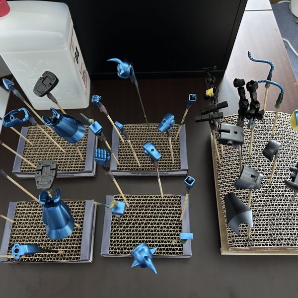 HGグフをキャンディ塗装で製作中。現在はパーツの乾燥待ちです。 合わせ目を消すために太ももと腕関節のあとハメ加工を施し、合わせ目消し→捨てサフ→パテ盛りと磨き直しを行い改めて塗装。肩アーマーのトゲ鋭利化も実施しています。メカサフ→光沢ブラックの塗装を全パーツに。明るいブルーパーツにはメタリックブルー→クリアブルーのキャンディ、暗いブルーにはメタリックブラック→クリアブルーのキャンディ。関節他黒系のパーツにはメタリックブラック→クリアブラック。モノアイレールだけは光沢ブラックで終え、オレンジのクリアパーツはそのまま使用する事に。（5枚目）