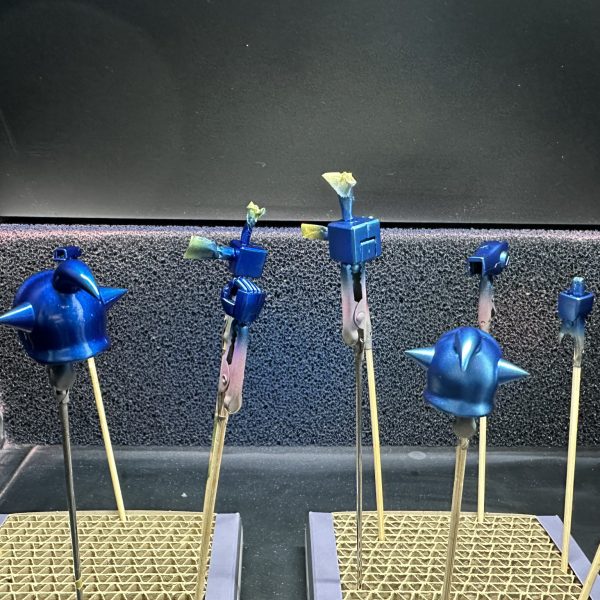HGグフをキャンディ塗装で製作中。現在はパーツの乾燥待ちです。 合わせ目を消すために太ももと腕関節のあとハメ加工を施し、合わせ目消し→捨てサフ→パテ盛りと磨き直しを行い改めて塗装。肩アーマーのトゲ鋭利化も実施しています。メカサフ→光沢ブラックの塗装を全パーツに。明るいブルーパーツにはメタリックブルー→クリアブルーのキャンディ、暗いブルーにはメタリックブラック→クリアブルーのキャンディ。関節他黒系のパーツにはメタリックブラック→クリアブラック。モノアイレールだけは光沢ブラックで終え、オレンジのクリアパーツはそのまま使用する事に。（6枚目）