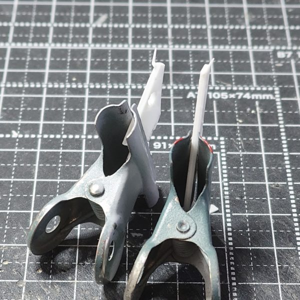 ガンダムアーティファクト第1弾のhi-νガンダムの頭部改修完成【頭部2】①アンテナブレードの小さいほうもプラ板で切り出し、持ち手のプラ板に接着してヤスリで整える②頭部のバルカンディテールを追加。エポパテを棒状にしたものを接着。③頭部は3パーツ構成にしました。今までの改修はフェイス部分を別パーツ化して、2パーツ構成でした。しかし、最後にフェイス部分をスライドしてはめ込む時にうまく入らない、ラピーテープの目が取れたりと苦戦するのでアーティファクトのガンダム系のひさし＆角で、上記の問題を解決することにしました。口も別パーツ化することでシャープ化、塗り分けがきちんとできる利点を得れると思います。問題点は、小さすぎてピンセットではじいて紛失しまくりです(-_-;)④原型と比較　1弾のガンダム系はしょうがないよね。最新弾のνガンダムは改修の必要ない出来。バンダイの技術はすげーや(>_<)あとは、塗装してスミイレがきれいに出来ること願うまでです(>_<)（2枚目）