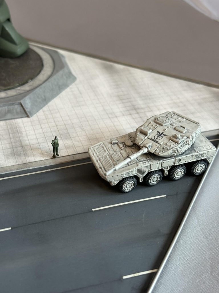首都防衛大隊っぽいAFVを、と思っておりまして、トミカプレミアムより「1/119&nbsp;陸上自衛隊１６式機動戦闘車」を召喚、一回バラして塗装して自作の首都防衛大隊エンブレムなどを貼り付けてそれっぽく仕上げました。ジオン兵はザク地上戦セットのものを塗装いたしました。アスファルトは1000番の耐水ペーパーです。