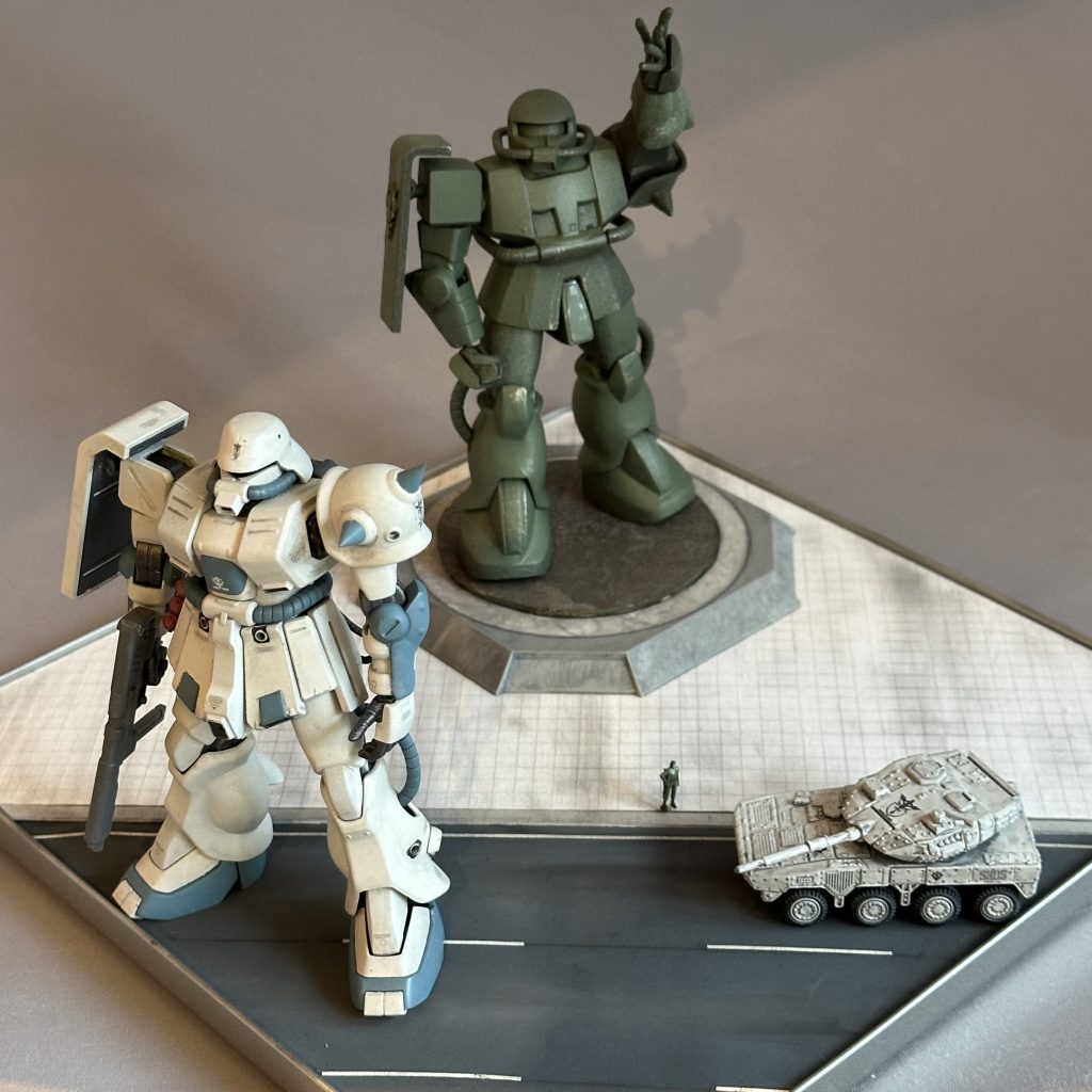 なんて現地レポート画像風に、旧キットのMSVザクマインレイヤーを利用したヴィネットを作成してみました。当時「1/144スケールの理想形のザク」と言われたキットであるマインレイヤーですが、21世紀の現在においては現行キット並べるには少々エモ過ぎますw旧キットのスタイルを生かしたまま、現行キットと並べるため、マインレイヤーザクさんには「ズムシティに設置された実物大ブロンズ像」になってもらいました。アート作品ならデフォルメされていても問題ないよねっ！