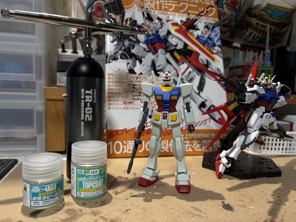 冒頭でも述べましたが、トップコートに今回初めてエアブラシ使ってます。今までトップコートは缶スプレーで吹いていたんですが、結構消費量多くてすぐ無くなるし、缶の処分が面倒くさいしで、サステナブル模型活動の一環でエアブラシ導入。長い目で見ればこっちの方が経済面で優位になるはず。ツヤ消しと半ツヤクリヤー塗料を半々にブレンドして、3/4ツヤ消しくらいを目指して吹いてみました。真ん中の初代様は組み立て体験会でもらったもの。今回のエアブラシ練習台になって頂きました。あとは制作テクニック本も大いに参考にしています。ストライク用のデカールもついてきて大変良い本でした◎