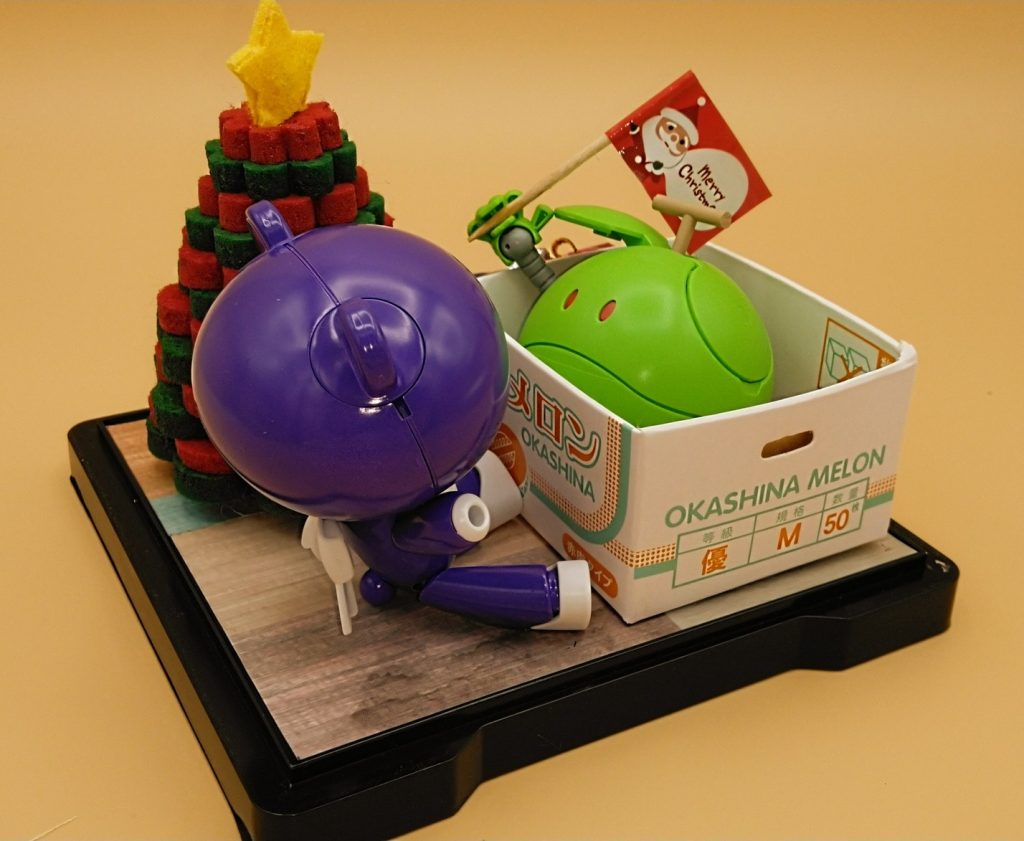 クリスマスプレゼントを開けたら中からメロンに扮したハロが出てきてビックリ！なシチュエーションです。こちらは数年前にクリスマスプレゼントの一環として、妻にプレゼントした物です。プチッガイの色は妻の好きな紫色、ハロには妻の好物のメロンになってもらいました(gundam-kao2)