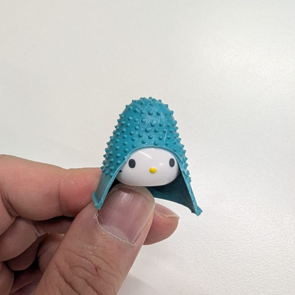 そんな訳でジェネリックマンダラの制作過程です。まずは頭、仕事を選ばない女帝ことキティさんの生首にいい感じにカットした指サックを被せます。あとはピックをいい感じにカットしてV字アンテナを再現したら完成です。次回は胴体です。（1枚目）