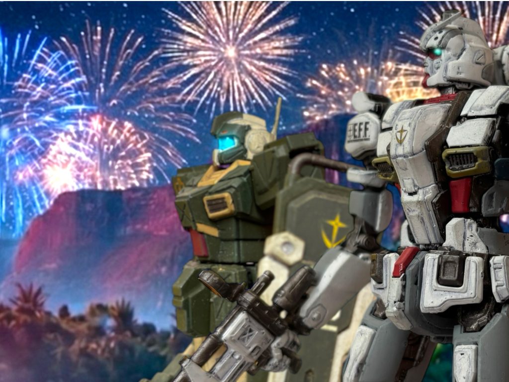 　機体を歩ませ始めると、基地のある西の方からドカンと派手な音がした。西の空が、けたたましい爆発音であふれると、強烈な光が何度も炸裂した。『気が早いな、こういうのは００００（ゼロゼロまるまる）にやるんじゃないのか？』　イギーが楽しそうに言う。『みんな、終わるのを待っていたのさ。』帰りが遅くなるがと、呟いた後、ヘントからまた指示が飛ぶ。『みんな、機体を止めてハッチを開けろ。』せっかくなら、肉眼で見よう、と呼び掛ける。　ミヤギはハッチが開ききる前に、シートから腰を浮かす。目を輝かせて空を見ると、わあ、と思わず声をあげた。『お届け物でーす。』茶化すような声が、ジム・ストライカーの外部スピーカーから聞こえたかと思うと、コクピットハッチの傍に、その巨大な掌がグンと迫った。上には、イギーからの”お届け物”、ヘントが乗っている。「こっちだ。」ハッチから身を乗り出していたミヤギの手を引く。「危な……っ！」思わず足をすくめたミヤギの体を強引にぐいっと引っ張ると、抱き締めるようにしてミヤギを抱きとめる。「……ちょっと……！」ひやりとしたのと、抱き締められている羞恥心とで、頬が赤くなる。「すまん。だが、今日くらいはいいだろう。」抱きしめる腕の力は、全く緩まる気配がない。