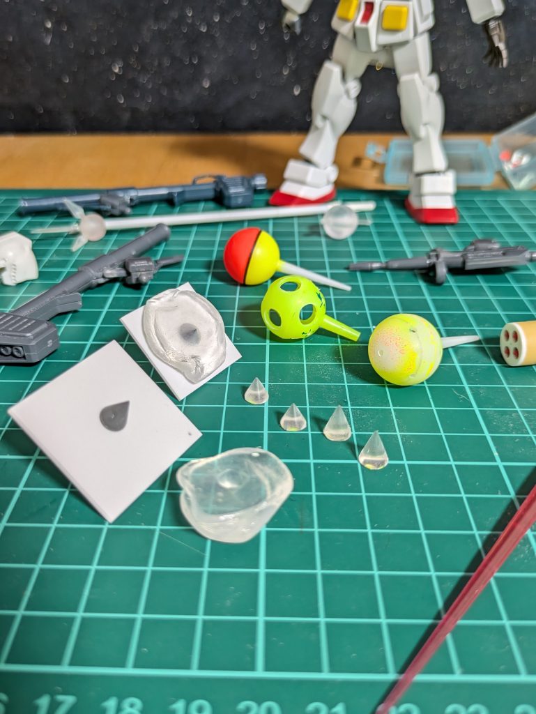 …ぐちゃぐちゃ…😅今回も釣り用の〘浮き〙を使っております😋真ん中の少し下にあるクリアーのかたまりは、お湯丸で作った〘型〙😚ガンダムハンマーとハイパーハンマーのトゲトゲ複製の為、２種類のトゲをレジンで作っております🤭それよりもずっと奥…ガンダムの足元にございますのがビームジャベリン😚その少し手前にある球体…ビームジャベリン先端を頑張って作ったはいいものの私の持つイメージよりも大きく作りすぎてしまった為却下😨…失敗作でございます😭😭😭💦.&nbsp;