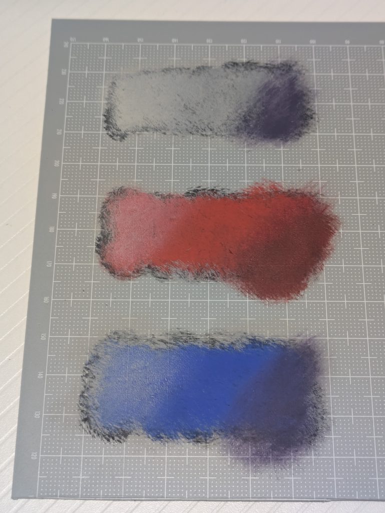 全体に陰影をつけるときは、大雑把に左上に光が当たり右下に影が差しているイメージで塗装しています。逆でも良いですし、異なる方向感でも良いのでしょう。基本色のときはポンポン叩いて塗りましたけど、陰翳、明暗をつけるときはカサカサにした筆をこするようにして塗料を乗せています。サムネに合わせて写真の上がガンダムの白部分、中がゲルググの赤、下がデュエルの青と同じ色を使って明暗をつけた結果です。影の部分は濃紺、濃い紫または基本色より明度を落とした色を使っています。ゲルググのときはダークレッドにしました。ガンダムやデュエルは紫系の濃紺(オックスフォードブルー)を使いました。ついつい黒を使いたくなりますが、モノの本によると影の表現には黒は使わないそうな。