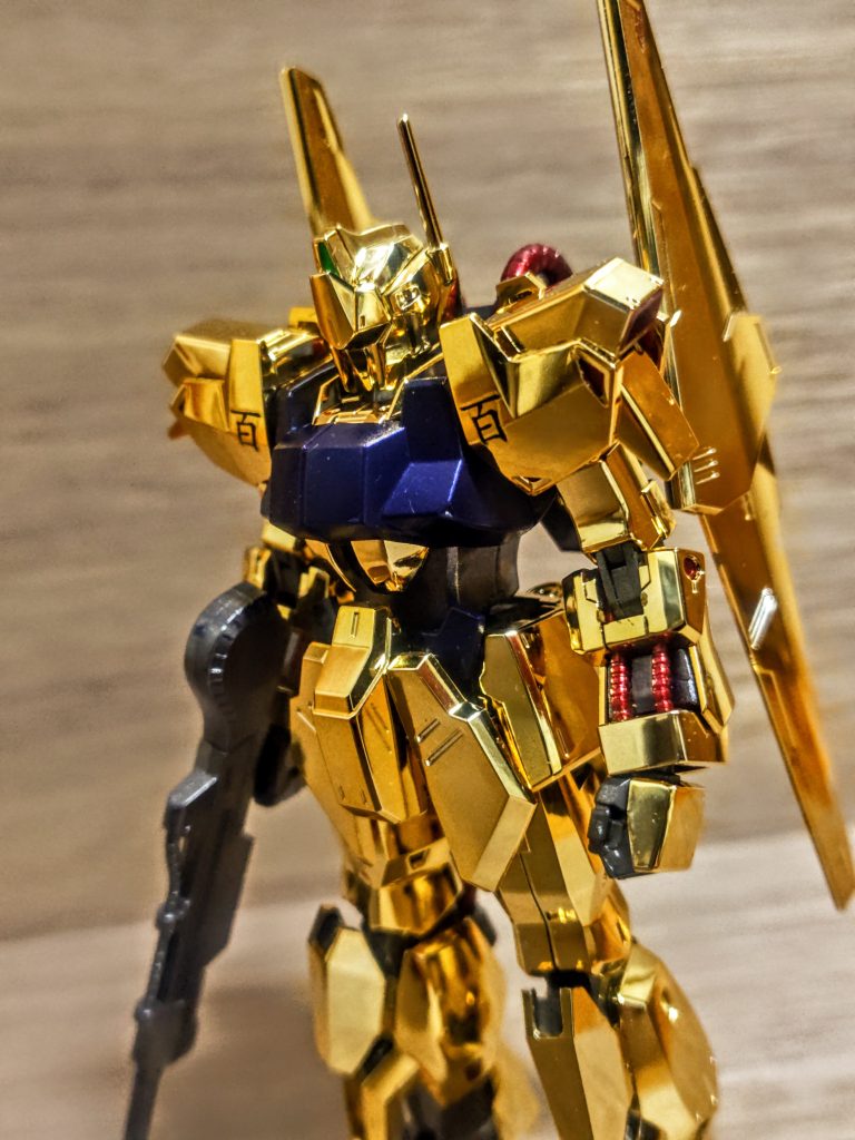 それが全身なんだから、そりゃ嬉しいでしょうよ。その証拠に私の作る機体では珍しく、今回は「百」しかデカール貼ってません（笑）。奇跡でしょ、とはいえ貼れば貼るほど余白が目立つ気がして、それをトップコートで隠し難いので今回は百オンリーです。赤いパイプラインだとか、なかなか色分けも素晴らしいし。ちなみにランナー塗装からのゲートあとは、ガンダムマーカーのリアルタッチ系で同じ赤や青を塗ればお手軽に目立たなくなります。今回のゴールドのメッキパーツの禿げた所は同じくリアルタッチマーカーのイエローで、これも簡単に目立たなくさせれます。気になったところは、頭部のクリアパーツの上にシールを貼るという謎の構造ですかね。全くもって意味がわかりません。私は当然の事ながら先にシールを貼り、その上からクリアパーツをかぶせました。こうする事でシールが奥の方に行き普段は反射しないので黒にしか見えず、目にライトを当てると赤に反射するという二度美味しい顔になります。「そんなの当たり前やろ」百式らしくてどちらも楽しみたいので。