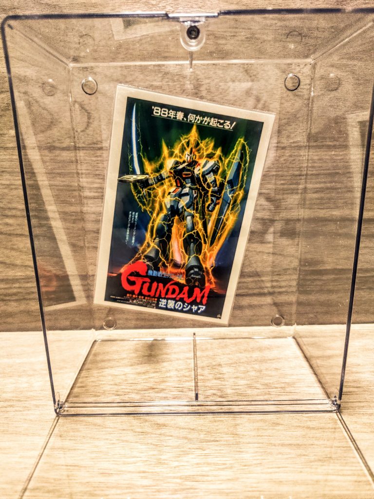 さっそくね、適当な位置にエル字金具をセットして接着。それを隠すべく背景ポスターを上から貼りましょ。ポスターに適当な細長い穴をカッターで開けて、そこからエル字金具が飛び出しているイメージ。そんな感じでうまい具合に配置しましょ。(恐ろしく適当な説明)上の画像だと丁度右手の上にカッターで細長い切れ込みを入れています。そこを通って、裏から前にエル字金具が出てきていますね。(わかりにくい（笑）)エル字の金具は100均のものを持ってきましたが、ちょっと歪んでたからカタカタなります。気に入らないので昔買った同じ物のホームセンターのに差し替えました。やっぱり違いますね、ホームセンターのだとバチッと平面が出て接着しやすいです。