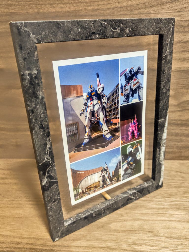 そしてダイソーさんでフォトフレームを購入。凄いですね、本当ダイソーさんは良いものを作ってくれます。これもちょっと石っぽい塗装がされていて高級感もありますからね、良く出来ています。一緒に500円ケースも手に入れられたので、またサザビーも作らないとね。さて、フレームの中の写真はららぽーと福岡さんのガンダム立像の画像をセブンイレブンさんでポストカード風にハガキ印刷。プリンターで操作して複数の画像をまとめて1枚に印刷出来るんです。