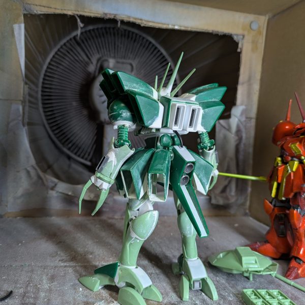 前回脚部の投稿をしましたが、この時は腕を小型化するため分割して幅詰めして接着し、パテ埋めまでしていて、乾燥待ちの状態でした。そこから整形できるまでかなりかかるかと思われたのですが、なぜか一発で形が決まってしまいました。そこで腰のスカートに着手したのですが、可動必須とはいえ、そこまで派手な可動域は必要なかったので、単純にスプリング接続でいいと判断して工作してみたら、これも短時間で出来てしまいました。試しに全身を組み上げてみたところ、思わずハンマハンマだ！と驚いてしまい、早く今まで見て頂いていた皆様に見てもらおうと思い、急遽投稿致します。後の工作は、導力パイプくらいです。足元のパーツは、各部バーニアで、塗装後接着するため分割しておいたものです。スカートは、バーニアを分割したあと、設定を参考に、下というか内側の部分をプラ板で追加造形しています。実は脚部はフレームを脛に挿しただけの状態なので、プラプラで直立させるのが精一杯でした。後はパイプを設置し、細かいディテールを追加すれば本体は完成なので、制作途中の投稿は最後となります。次は完成品を投稿しますので、暫くお待ち下さい。ありがとうございました。（4枚目）