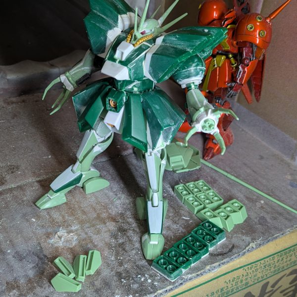 前回脚部の投稿をしましたが、この時は腕を小型化するため分割して幅詰めして接着し、パテ埋めまでしていて、乾燥待ちの状態でした。そこから整形できるまでかなりかかるかと思われたのですが、なぜか一発で形が決まってしまいました。そこで腰のスカートに着手したのですが、可動必須とはいえ、そこまで派手な可動域は必要なかったので、単純にスプリング接続でいいと判断して工作してみたら、これも短時間で出来てしまいました。試しに全身を組み上げてみたところ、思わずハンマハンマだ！と驚いてしまい、早く今まで見て頂いていた皆様に見てもらおうと思い、急遽投稿致します。後の工作は、導力パイプくらいです。足元のパーツは、各部バーニアで、塗装後接着するため分割しておいたものです。スカートは、バーニアを分割したあと、設定を参考に、下というか内側の部分をプラ板で追加造形しています。実は脚部はフレームを脛に挿しただけの状態なので、プラプラで直立させるのが精一杯でした。後はパイプを設置し、細かいディテールを追加すれば本体は完成なので、制作途中の投稿は最後となります。次は完成品を投稿しますので、暫くお待ち下さい。ありがとうございました。（6枚目）