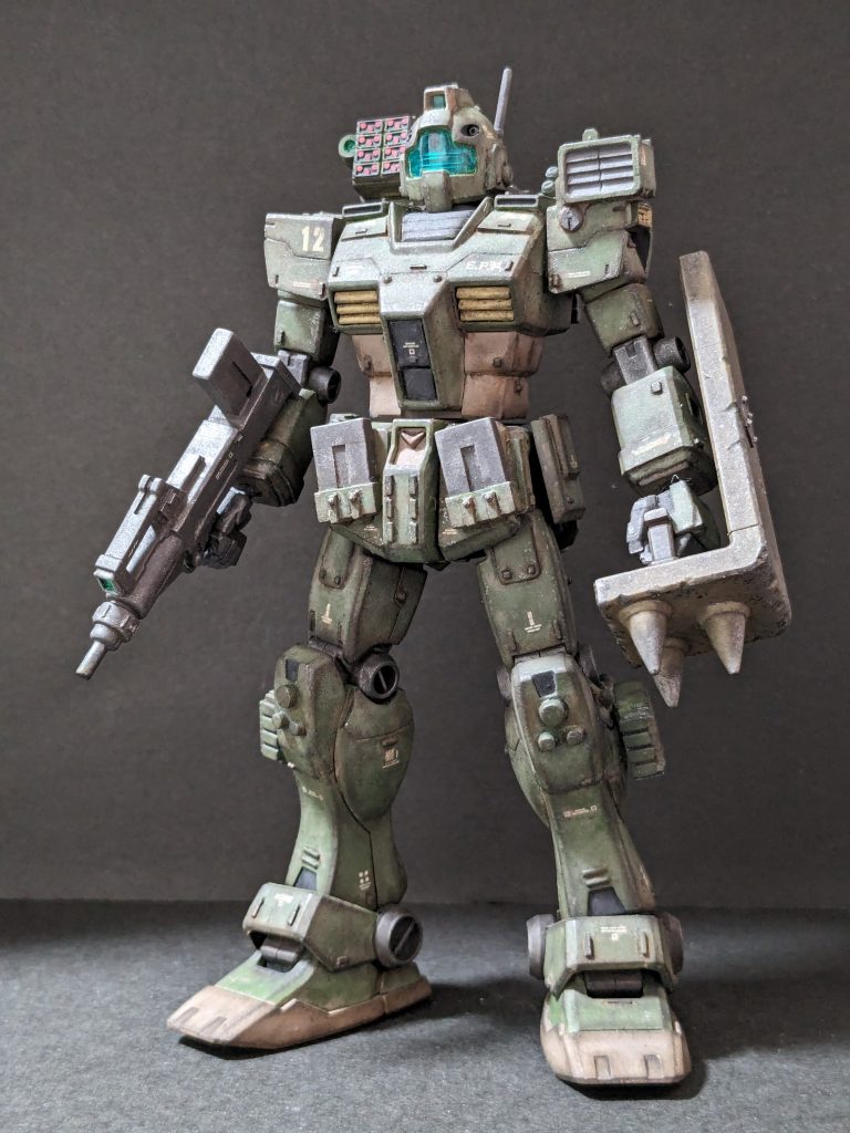【正面】ミリタリー調のカラーリングにして強めにウェザリング。ぶん殴りたいので拾ったスパイクシールドを愛用ということに。その他の追加兵装として脚部ミサイルポッド×8と肩越しにマイクロミサイル×24。フロントスカートに予備マガジン×2。
