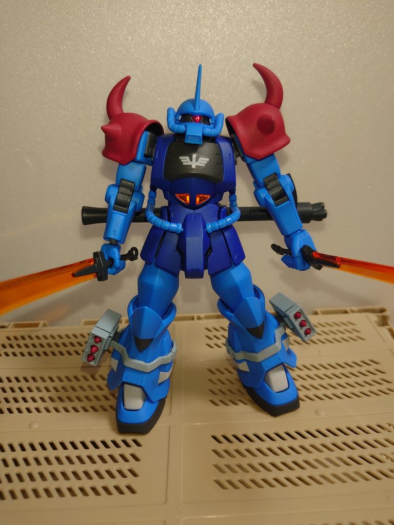 マントなしで、正面から。イメージ元は、グフとイフリートの間くらい、という感じで作りました。赤い肩や、足の白い差し色もその名残です。モノアイはハイキューパーツのSPプレートにUVレジンを盛っています。コックピットのクリアーはそのままだと背面の青が透けて印象がぼやけてしまうので、UVレジンを充填してアルミホイルで反射層を作ってあります。