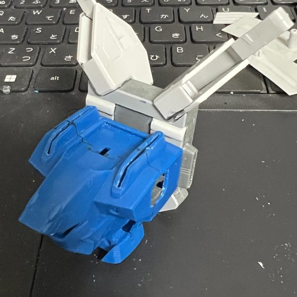 正面からポリキャップが見えるのでプラ板で隠し。追加パーツも空間ができるのでプラ板を貼り付け。これだとはまらなくなるので、装着後に見えなくなる上側のスラスターを削り取って対応。キットのままだと追加パーツの内側と本来のバックパックが干渉してぴったりつかないため、バックパック側の干渉部分を削って調整。（3枚目）