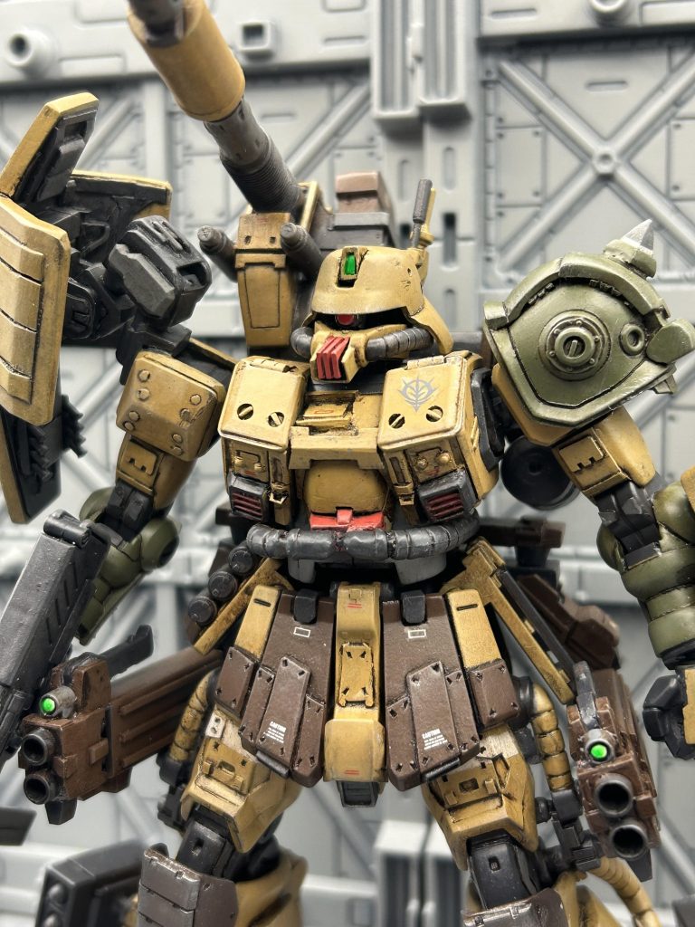 【自分設定】ジオンの敗戦に伴い、軍事物資を廃棄または各地に隠匿することになった。その中でFZ型ザクの一部がその他物資とともに地上残留部隊に引き渡された。しかし宇宙用のサブスラスターなど地上には不向きな仕様も多かった為、ヨーロッパ戦線での現地改修ノウハウなどを活用し、FZ型地上仕様として一次改修が行われた。その後アフリカ方面の部隊に合流した後、F型,J型に比べて高い機動性を活かしドム、ドワッジに随伴し支援する為の機体に改修された。改修時にはアフリカ戦線で撃破されたザクキャノンや強奪した連邦軍のジム系(F型など)機体の装甲材などを使用した。ロンメル隊にて運用されたが第一次ネオジオン抗争前に損失した。