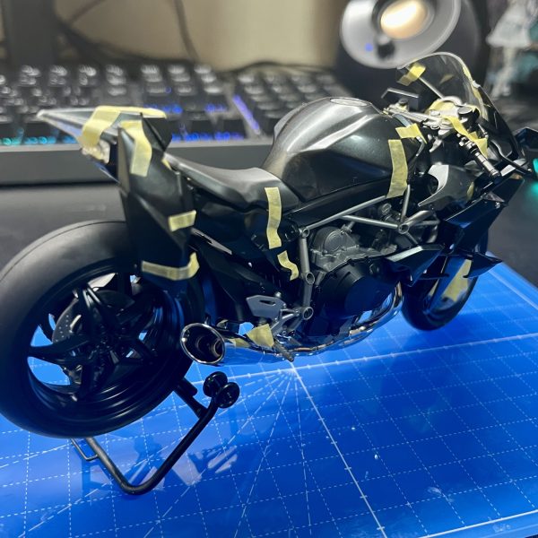 皆さま、明けましておめでとうございます。今回制作中のフラッグはコンセプト段階で可変機構をオミットする方向で進めていたため、長距離移動用のサポートメカ的なものがあればいいなと考えていました。そこで目を付けたのは戦闘機モチーフのNinja H2R、そうバイクです。フラッグ自体戦闘機っぽい意匠が多いので、Ninjaは結構相性が良いのでは？と思い、制作を進めています。バイクのプラモ自体は実は初めてということもあり、まだ仮組みが終わった段階ですが、塗装の関係上接着がほぼできない＋全然ハマらないビス止め(何度もビスを紛失しかける)という苦行を新年早々味わうことになりました。私自身バイクの知識が皆無なので、構造、部品云々はさっぱり分かりません。ということで今回は実車の設定ガン無視で制作を進めていきます(かっこよければそれで良し)。改造としては基本的に見た目が大きく変わる改造…というよりフラッグに合わせて形状を調整&ビス固定をなるべく減らす改造がメインとなります(サイズ感はピッタリなので)。その他、武器を懸架できるようにするとかアクションベースで固定できるようにするとか色々検討中です。長文失礼しました。それでは今年もよろしくお願いします。（4枚目）