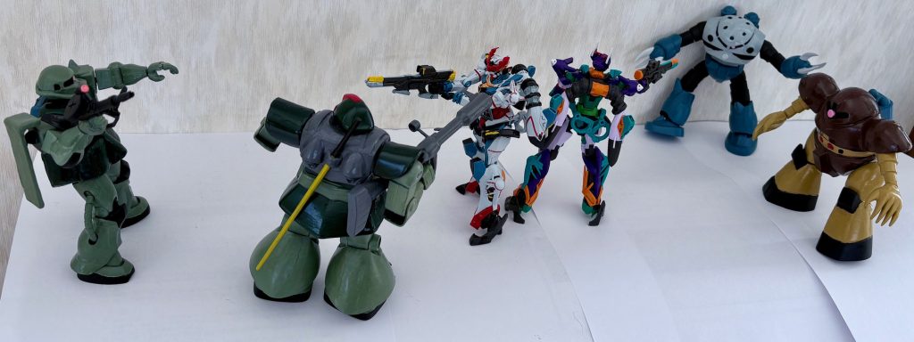 撮影の裏側。デジラマ加工でカッコよくしているが、実際は白い壁と白紙の上にガンプラを置いて撮影している。複数のガンプラを使うので、パノラマで撮った。