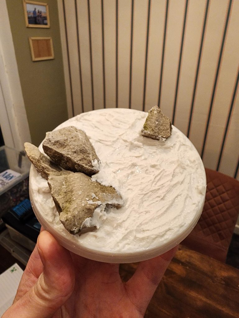 家中に散らばっていた古い部品で土台を作ることができました。チョコレートの容器の蓋、庭の石、浴室のタイルの目地材などです。散らかる前に、模型と石を素早く配置して、ちょうどいい構図を探しました。I was able to make a base from old bits lying round the house. A lid from a chocolate tub, stones from the garden and some bathroom tile grout. Before getting messy I quickly arrange the model and the rocks to find a nice composition.