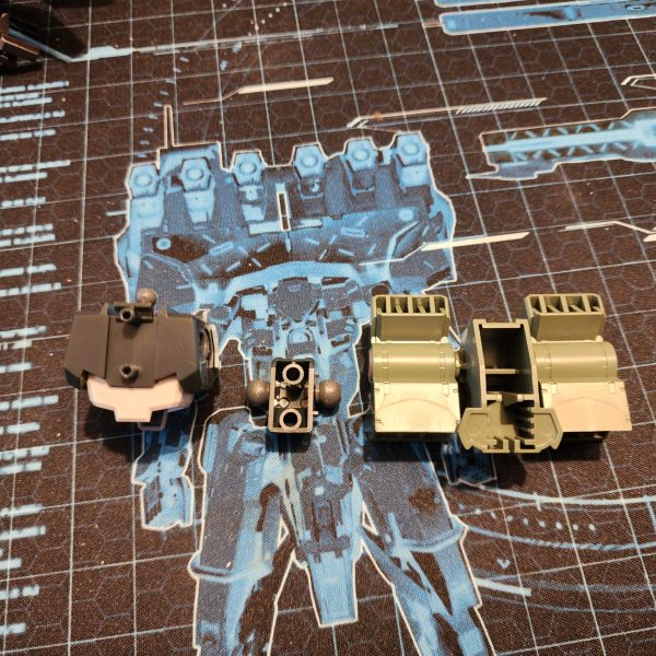 まずは、ストライカーのフライトギアをケルディムに取り付けるのが良いスタートになると思います。ケルディムのパックは、突起部分を切り落とすとストライカーのパックに収まることに気づきました。これなら簡単に接続できそうです。後で少し切り込みを入れて調整すれば、うまくいきました。 バックパックを組み立てると、頭の後ろに大きな穴が開いてしまい、それを覆うパーツがありません。そこで、ちょっと改造してプレートで覆ってみることにしました。寸法を測ってサイズに合わせて切り抜き、セメントで接着して滑らかに研磨します。さらに、ナイフを使ってパック上部の形状に合わせて窪みを切り落とします。このような模型製作は初めてですが、なかなか良い出来栄えだと思います。To begin, attaching the flight gear from the Striker to the Cherudim should be a nice way to kick things off. I noticed that the Cherudim pack will slot inside the Striker pack if I cut away some of the protruding shapes. This would be an easy way to make the connection. Some hacking and chopping later, it works.When mounted, the back pack has a huge hole behind the head and no pieces to cover. I decided to try my hand at some modification and cover it with a plate. I measure and cut to size. Glue it on with cement and sand it for a smooth finish, I also use a knife to slice away into the recess to match the shape on the top of the pack. This is the first time I've ever done this type of model work and I think it's looking great.（2枚目）