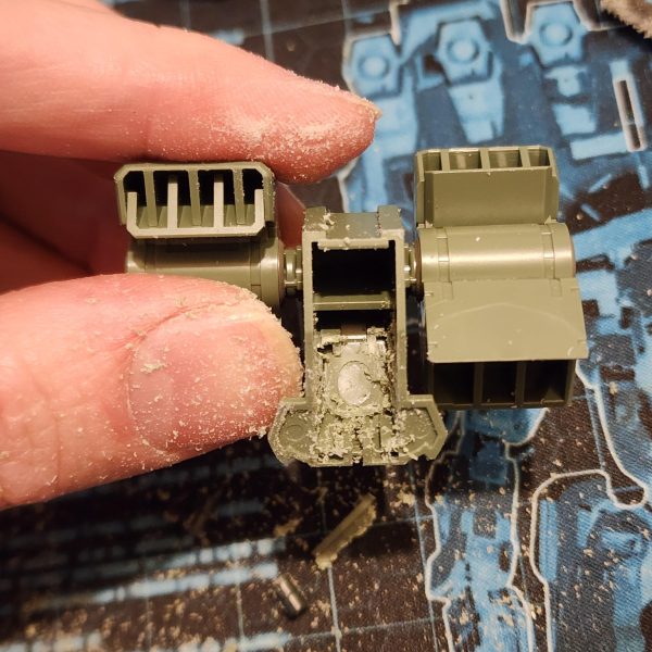 まずは、ストライカーのフライトギアをケルディムに取り付けるのが良いスタートになると思います。ケルディムのパックは、突起部分を切り落とすとストライカーのパックに収まることに気づきました。これなら簡単に接続できそうです。後で少し切り込みを入れて調整すれば、うまくいきました。 バックパックを組み立てると、頭の後ろに大きな穴が開いてしまい、それを覆うパーツがありません。そこで、ちょっと改造してプレートで覆ってみることにしました。寸法を測ってサイズに合わせて切り抜き、セメントで接着して滑らかに研磨します。さらに、ナイフを使ってパック上部の形状に合わせて窪みを切り落とします。このような模型製作は初めてですが、なかなか良い出来栄えだと思います。To begin, attaching the flight gear from the Striker to the Cherudim should be a nice way to kick things off. I noticed that the Cherudim pack will slot inside the Striker pack if I cut away some of the protruding shapes. This would be an easy way to make the connection. Some hacking and chopping later, it works.When mounted, the back pack has a huge hole behind the head and no pieces to cover. I decided to try my hand at some modification and cover it with a plate. I measure and cut to size. Glue it on with cement and sand it for a smooth finish, I also use a knife to slice away into the recess to match the shape on the top of the pack. This is the first time I've ever done this type of model work and I think it's looking great.（3枚目）