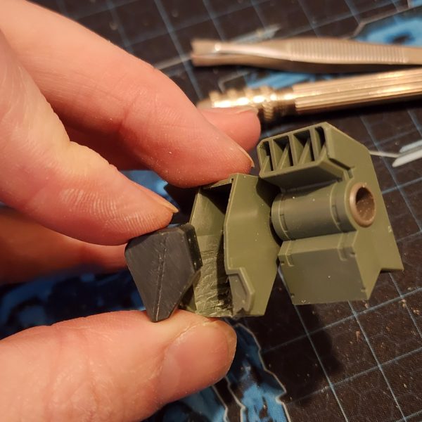 まずは、ストライカーのフライトギアをケルディムに取り付けるのが良いスタートになると思います。ケルディムのパックは、突起部分を切り落とすとストライカーのパックに収まることに気づきました。これなら簡単に接続できそうです。後で少し切り込みを入れて調整すれば、うまくいきました。 バックパックを組み立てると、頭の後ろに大きな穴が開いてしまい、それを覆うパーツがありません。そこで、ちょっと改造してプレートで覆ってみることにしました。寸法を測ってサイズに合わせて切り抜き、セメントで接着して滑らかに研磨します。さらに、ナイフを使ってパック上部の形状に合わせて窪みを切り落とします。このような模型製作は初めてですが、なかなか良い出来栄えだと思います。To begin, attaching the flight gear from the Striker to the Cherudim should be a nice way to kick things off. I noticed that the Cherudim pack will slot inside the Striker pack if I cut away some of the protruding shapes. This would be an easy way to make the connection. Some hacking and chopping later, it works.When mounted, the back pack has a huge hole behind the head and no pieces to cover. I decided to try my hand at some modification and cover it with a plate. I measure and cut to size. Glue it on with cement and sand it for a smooth finish, I also use a knife to slice away into the recess to match the shape on the top of the pack. This is the first time I've ever done this type of model work and I think it's looking great.（4枚目）