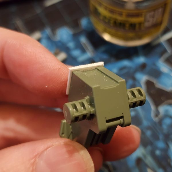 まずは、ストライカーのフライトギアをケルディムに取り付けるのが良いスタートになると思います。ケルディムのパックは、突起部分を切り落とすとストライカーのパックに収まることに気づきました。これなら簡単に接続できそうです。後で少し切り込みを入れて調整すれば、うまくいきました。 バックパックを組み立てると、頭の後ろに大きな穴が開いてしまい、それを覆うパーツがありません。そこで、ちょっと改造してプレートで覆ってみることにしました。寸法を測ってサイズに合わせて切り抜き、セメントで接着して滑らかに研磨します。さらに、ナイフを使ってパック上部の形状に合わせて窪みを切り落とします。このような模型製作は初めてですが、なかなか良い出来栄えだと思います。To begin, attaching the flight gear from the Striker to the Cherudim should be a nice way to kick things off. I noticed that the Cherudim pack will slot inside the Striker pack if I cut away some of the protruding shapes. This would be an easy way to make the connection. Some hacking and chopping later, it works.When mounted, the back pack has a huge hole behind the head and no pieces to cover. I decided to try my hand at some modification and cover it with a plate. I measure and cut to size. Glue it on with cement and sand it for a smooth finish, I also use a knife to slice away into the recess to match the shape on the top of the pack. This is the first time I've ever done this type of model work and I think it's looking great.（6枚目）