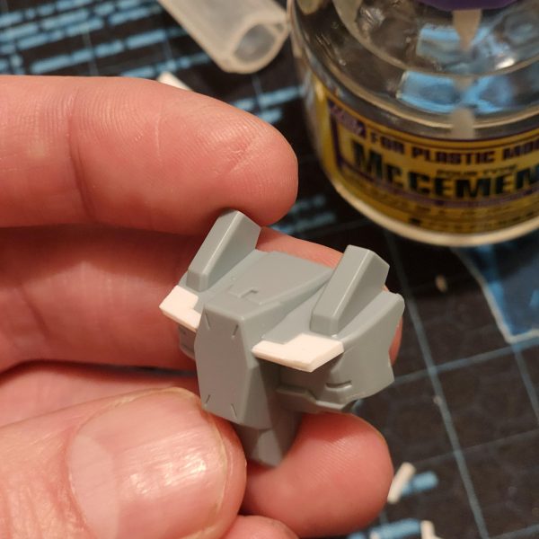 正直に言うと、これは見た目よりずっと大変でした。まず、側面の丸い光学部品を切り取りました。それから、プラスチックのプレートを使って胸部を拡張したらすごくクールになるんじゃないかと思いつきました。スーパーカーのフロントみたいに。穴も隠せるし。両側の形を合わせるのに、何度か試行錯誤して何度も切り込みを入れました。すごく小さくて扱いにくいんです。それから、装甲ブロックを胸部に貼り付けようとしたのですが、ブロックの裏側の表面積が足りなくて接着できませんでした。そこで、裏側にプレートを追加して滑らかな表面を作ることにしました。一応はうまくいきましたが、壊れやすいのではないかと心配です。とにかく、いい感じに仕上がったと思います。結果には満足しています。Let me tell you, this was a lot harder than it might seem.I started by cutting away the round optics from the side. Then I thought it would be cool as hell to extend the chest with some plastic plate. Kind of like the front of a super car. It would help to cover the hole too. It took me a few tries and lots of cuts to get the shape matching on both sides. They're so tiny and fiddly. I then try to stick the armour blocks to the chest but theres not enough surface area of the back of the blocks to adhere to. I decide to add plates to the back and create a smooth surface. It kind of works, but I'm worried they might be fragile.Anyway, I think it's looking good. I'm happy with the results. (3枚目)