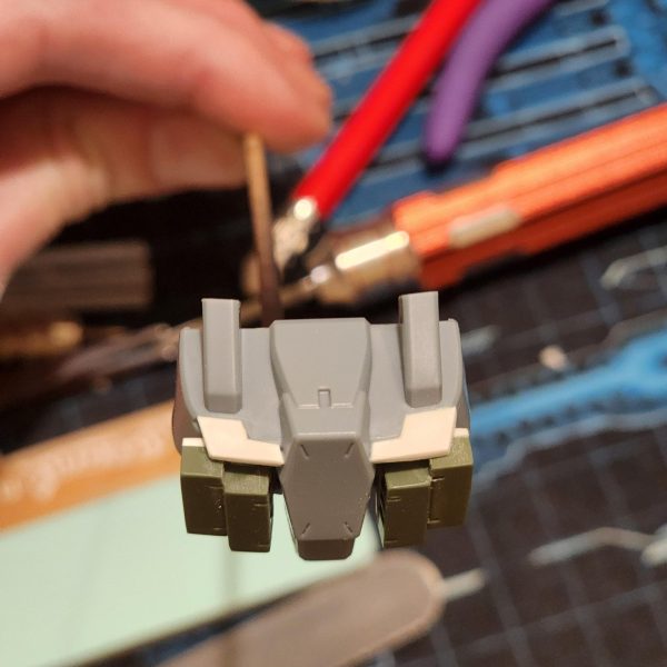 正直に言うと、これは見た目よりずっと大変でした。まず、側面の丸い光学部品を切り取りました。それから、プラスチックのプレートを使って胸部を拡張したらすごくクールになるんじゃないかと思いつきました。スーパーカーのフロントみたいに。穴も隠せるし。両側の形を合わせるのに、何度か試行錯誤して何度も切り込みを入れました。すごく小さくて扱いにくいんです。それから、装甲ブロックを胸部に貼り付けようとしたのですが、ブロックの裏側の表面積が足りなくて接着できませんでした。そこで、裏側にプレートを追加して滑らかな表面を作ることにしました。一応はうまくいきましたが、壊れやすいのではないかと心配です。とにかく、いい感じに仕上がったと思います。結果には満足しています。Let me tell you, this was a lot harder than it might seem.I started by cutting away the round optics from the side. Then I thought it would be cool as hell to extend the chest with some plastic plate. Kind of like the front of a super car. It would help to cover the hole too. It took me a few tries and lots of cuts to get the shape matching on both sides. They're so tiny and fiddly. I then try to stick the armour blocks to the chest but theres not enough surface area of the back of the blocks to adhere to. I decide to add plates to the back and create a smooth surface. It kind of works, but I'm worried they might be fragile.Anyway, I think it's looking good. I'm happy with the results. (5枚目)