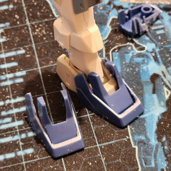 ケルディムが重くなってきた。安定性を高める必要がある。ブルーデスティニーのジャンク品から足をいくつか取り出し、外側の縁を削ってケルディムの足の前部に取り付けた。かなりフィット感が良い。ただし、いくつか隙間を埋める必要があるので、ベースにプレートを、トップに他のパーツを追加した。結果には非常に満足している。ソールの新しいプレートは個性がないのは分かっているが、全く問題ない。後で細かい部分を書き込めるかもしれない。一晩寝て頭の中で色々考えてみた結果、もっと簡単にできる別の方法を思いついた。後知恵は素晴らしいものだ。The Cherudim is getting heavier. Time to increase stability.Using some feet from a junk Blue Destiny, I carve away the outer edge and add them to the front of the Cherudim feet. It's a pretty good fit.I do however need to fill some gaps, so I add a plate to the base and some other parts to the top. I'm really happy with the outcome.I know the new plates on the soles have no character but I'm totally fine with that. Maybe I could scribe some details in later.&nbsp;After a night's sleep and replaying things in my head, I've come up with another way to do this which might have been easier.&nbsp;Hindsight is a beautiful thing.（4枚目）