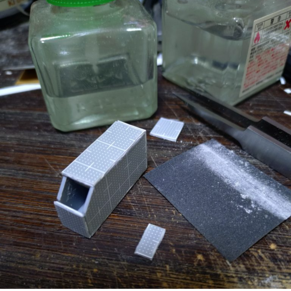 次はスクラッチのビームバズーカです。プラ板箱組みメインの工作なので面が7つの箱組みでとりあえず説明します。デザインは自分の頭の中にある何処かで見た様な、あるいは何かのイメージです………多分(笑)インスピレーションを大事にしてその時のノリで作るとオリジナル感がある物が自分の場合は出来上がる率が高くなると思ってるので、生き当たりばったりな感じは大事にしてますねぇ(笑)😊グリップ部分だけジャイアントバズの物を使い、他はプラ板箱組みで制作。プラ板はウェーブの目盛り付き1mmを愛用してます。これはいちいち測らなくても目盛りでだいたいのサイズが分かるのでオススメですよ😊プラ板を切り出す際は本当なら設計図のような物を描いて厳密に測って切り出すのがベストでしょうけど、面倒くさがりな私はいつも目分量です👍(笑)両サイドの大きい面のプラ板はガイドとなるので出来るだけきっちり同じ物になるように調整すると他のパーツを接着しても変に歪んだりしないのでこの辺だけはキッチリ押さえておいた方が良いです。隣のパーツとの接合部の角度を合わせるのも重要ポイントです。そして切り出したプラ板を接着して行きますがどうしても接合部に合わせ目が出来るので、接着剤は多めにドバっと付けましょう(笑)乾燥後にカナヤスリで整形しつつ、大きな隙間が出来てしまった場合は瞬着で埋めましょう。これで大体は埋まってくれます。