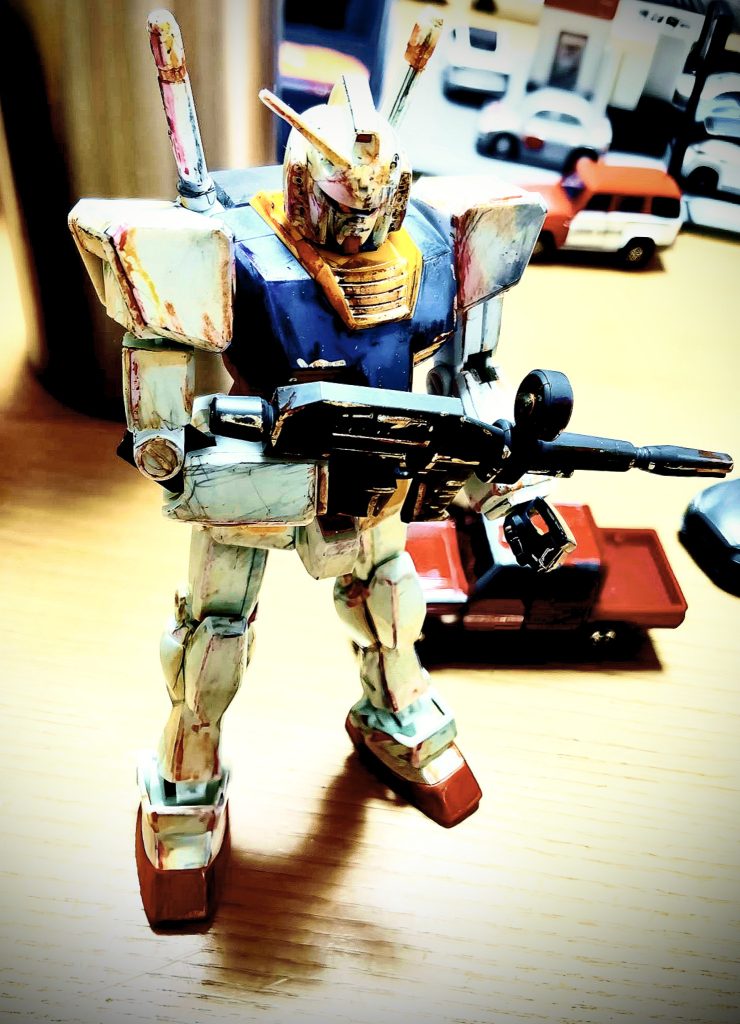 その時のガンプラブームのヤバさは、今の比ではありません。当時は、今のように、ほしいガンプラが売ってない!だの、発売日に並ばなきゃ!などの生ぬるいレベルではありませんでした。ガンプラ自体が全くどこを探しても売っていない状態でした。ガンプラ以外のパチモンガンプラでさえ、枯渇状態!あったとしても、1か2個。その1か2はサラミスであり、ガンダム武器セットだったのです。今みたいな、ネット情報も無く、発売日も完全黙秘のバン◯イ親方スタイルには、あるのかないのか?分からずに、異常な期待感で早朝からスーパーのおもちゃ売りばに並んでいたのです。並んでまで買えない!とプライドが許せないソフト森本君は、当時武器セットしか持っていなく、仕方なく本体をトイレットペーパーの芯5本とダンボールでフルスクラッチした、ペーパーガンダムを創り、武器を持たせていたのです。顔だけは、兄貴肌のジャイアン福田君が持っていたガンダムの箱の顔部分を切り取って貰い仮面のように付けていたのです。そう、こんな時代に並べばいいじゃん!は成り立たないのです。じゃあ、何故ワタシはガンプラを持っていたのか?自分は、スネ夫的な金持ちないやらしいヤツ?だと勘違いされるのは、しゃくにさわるので説明します。自分は学校帰りに親には内緒で、毎日のように、スーパーのおもちゃ売り場に行っていたのです。当然ガンプラ何か売ってません。目的はいつ入荷するか?の情報取得です。おもちゃ売り場のオバサンをお姉さんと呼び、それとなく、ガンプラの為にコミニケーションとスキンシップを高めて行くのです。そう恋愛ゲームときめきメモリアルのようなリアル好感度アップ作戦です。もう手段は選んで居られないそんな異常なガンプラブーム!しばらく通っていると、情に流された、お姉さんが、閉店間際に「 これホントは明日の朝棚に並べるんだけどちょっと見る?」とダンボールをこっそり開けてくれた時、ジムが待っていたよ!と顔を覗かせていたのです。お分かり頂けたでしょうか?当然積みプラなどやりたくても出来ない時代でした。逆に言えば、その時の氷河期の子供達がオトナになり、あの苦渋に満ちた苦い経験から、思わず目の前にあるガンプラを買って積みプラしてしまうのかもしれませんね。