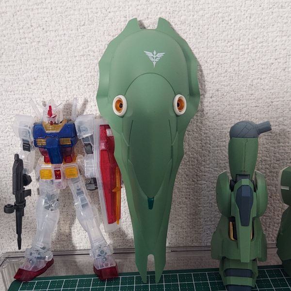 やっとバインダーが完成しました。先にファンネルを整形しておいて本当に良かった。先にも書いたとおり、バーニアは焼鉄色で塗装。ほかに、つや消しのトップコートの後に、ワンポイントとしてメタリックグリーンを入れてみました。サイコミュの増幅装置的なものと思っていただければ。双方とも水性ホビーカラーです。メガ粒子砲の砲口の、金はガンダムマーカーEXのイエローゴールド、黒は水性ホビーカラーのブラックです。同スケールのガンダムと並べるとこんな感じで、バインダーの陰に入ったらまるまる隠れてしまいますね。さて、残るは腰部です。現在各パーツに分けてトップコートを吹いたところまで進んでいますが、フロントアーマーはデカールを貼るためヒケの処理をしたところまでです。バインダーのアームにもひと手間加えて、この週末には完成予定です。（2枚目）