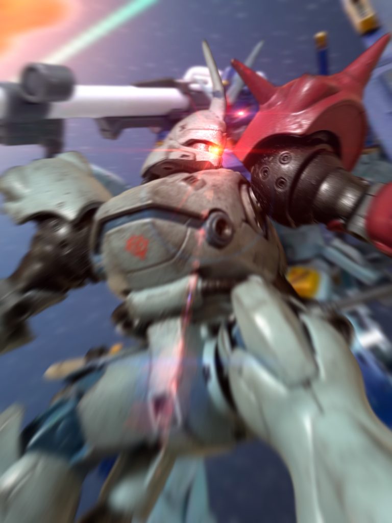 「貴様……貴様っ！！」　サラだけでなく、イアンまで殺された。　火器の弾薬は既に底を尽き、最後の手段とも言うべくビームサーベルを抜いている。　邪魔な敵機を斬り裂きながらガンダムに向かったが、一瞬見失う。ふと、後ろから衝撃。ガンダムが組みついてきていた。直接回線が開く。『いい腕だ、若造。』　何を、言っている——こいつは？　先ほど、こいつは、コロニー落としを糾弾した。　そして、こちらの仲間を虐殺した。　”分かっただろう”、と、裁定者じみたことを口走った。　つまり、戦争の悲しみに、過ちに、浸っていたはずだ。　それが、なんだ——この戦いの最中、今度は、古のサムライごっこにでも興じるつもりか？「無駄話など！」『敵ながら天晴れと言っている。こっちの若い連中とは、違う。骨がある！』　やはり、か。「……貴様、なめているのか！？」　馬鹿馬鹿しい。応じたくもなかったが、つい、応えてしまった。『違うな、わたしを超えてみせろと言っている！』　何が、違う。　なめているだろうが。　戦いは、自己実現の場ではない。　これは、生きるか死ぬかの——獣同士の、本能のぶつけ合いだ。　矜持などない。　大義などない。『敵でもいい……わたしを……わたしの哀しみと、闘いを、