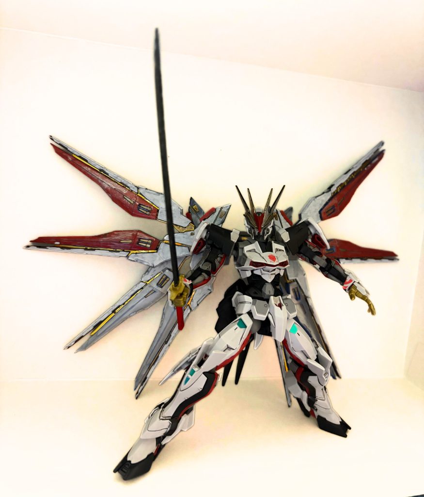 2. 最大の特徴：武装とギミックこの機体の象徴は、背面に装備された巨大なマルチユニットです。• ロードドラグーン:背中に装備された翼のようなパーツは、すべて遠隔操作兵器「ドラグーン」として射出可能です。• 変幻自在の合体機構:ドラグーンは分離して攻撃するだけでなく、手持ちの巨大な剣として合体させたり、盾として配置したりすることが可能です。• 防御能力:複数のドラグーンを機体前面に展開することで、鉄壁の守りを誇ります。