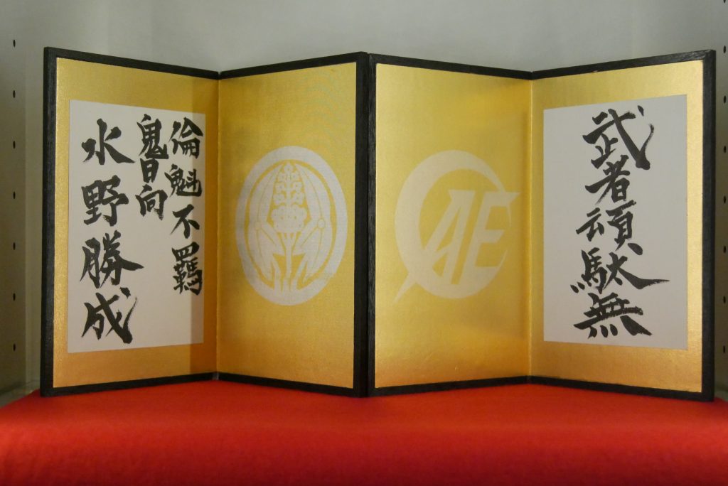 屏風は手作り。文房具店で金箔風折り紙をゲットし、文字はお友達の書道家に書いてもらいました。家紋とロゴマークは低出力のレーザーで加工。